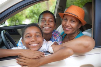 Portrait of mother and twin sons leaning on car window