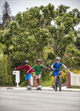 Boy on bicycle pulling friends on skateboards