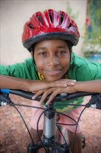 Portrait of Black boy leaning on bicycle handlebar