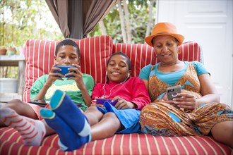Black mother and twin sons using cell phones outdoors