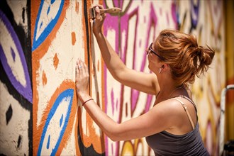 Caucasian woman painting mural on wall