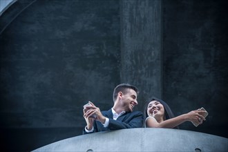 Low angle view of couple on balcony texting on cell phones