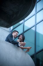 Low angle view of couple on balcony texting on cell phones