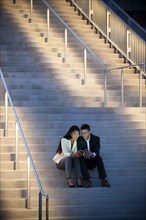 Couple sitting on staircase texting on cell phones