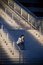 Woman sitting on staircase texting on cell phone