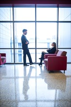 Businessman and businesswoman talking in office lounge