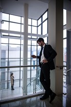 Businessman texting on cell phone near staircase