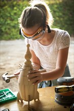 Caucasian girl hammering nails into birdhouse