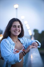 Portrait of smiling teenage girl leaning on railing