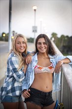 Portrait of smiling teenage girls leaning on railing