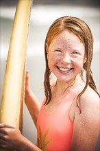 Portrait of smiling girl holding surfboard