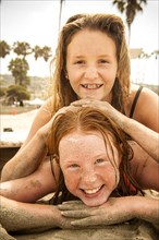 Portrait of smiling girls laying on beach covered with sand