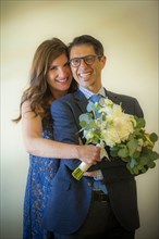 Portrait of smiling couple holding bouquet of flowers