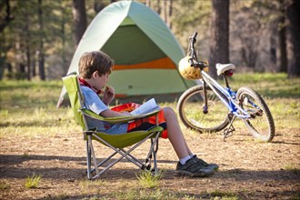 Caucasian boy reading book at campground