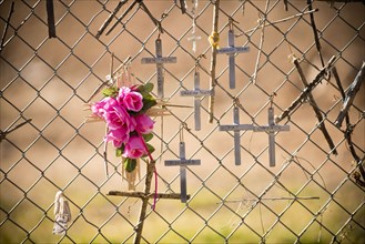 Crucifixes and flowers hanging on memorial fence
