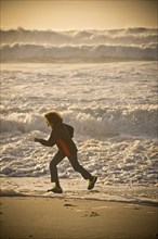 Mixed race boy running on beach