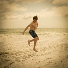 Caucasian boy jumping and splashing in ocean waves