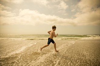 Caucasian boy running in ocean waves