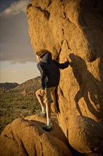 Mixed race boy standing on rock in desert