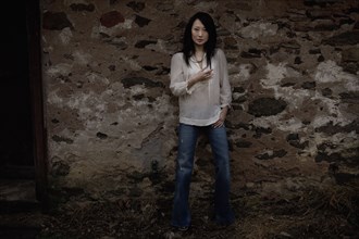 Serious Asian woman leaning against wall