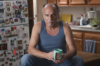 Serious Caucasian man drinking coffee in kitchen