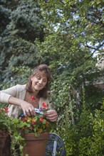 Caucasian woman clipping flowers in garden