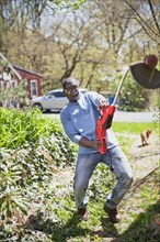Black man struggling with weed trimmer
