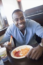 Black man eating french fries at diner