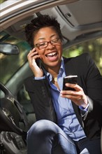 Black woman in vehicle using two cell phones