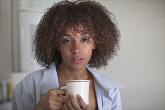 Serious mixed race woman drinking coffee