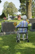 Older Caucasian woman visiting grave in cemetery