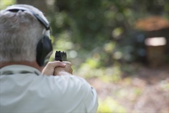 Older Caucasian man practicing with gun at shooting range