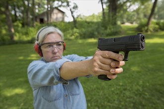 Older Caucasian woman practicing with gun at shooting range