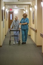 Older Caucasian woman walking with nurse in nursing home