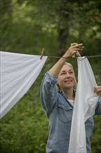 Older Caucasian woman hanging laundry on clothesline