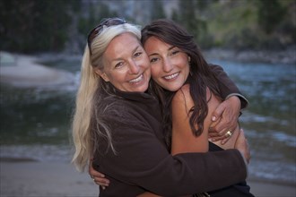 Caucasian mother and daughter hugging near lake