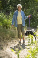 Older Caucasian woman walking dog on dirt path