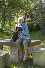 Older Caucasian woman hugging dog in park