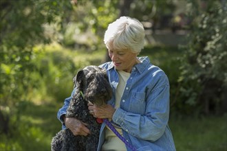 Older Caucasian woman hugging dog in park