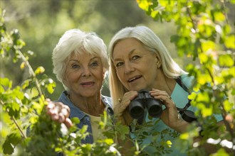 Older Caucasian women bird-watching outdoors
