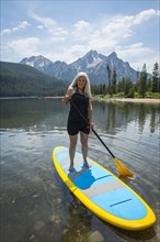 Caucasian woman standing on paddle board in lake
