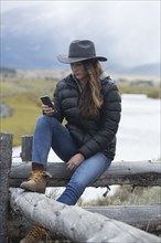 Caucasian woman using cell phone at rural river