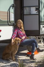 Caucasian woman petting dog at trailer