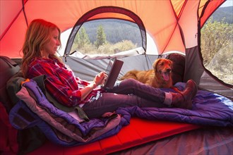 Caucasian woman using digital tablet in camping tent
