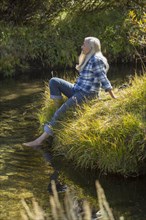 Caucasian woman dipping feet in river
