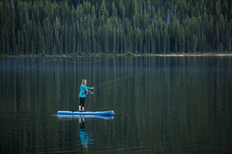 Caucasian woman fishing from paddle board in river