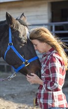 Caucasian woman hugging horse on ranch