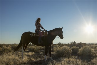 Caucasian woman riding horse in field