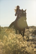 Caucasian woman riding horse on dirt path