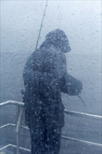 Caucasian fisherman standing on rainy boat deck